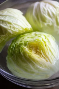 Prepare cabbage leaves by peeling them off the head and soaking them in cold water to crisp up