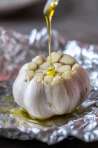 Prepare the garlic by cutting the top off the head to expose the cloves and drizzle with olive oil