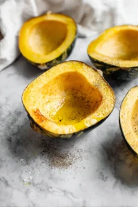 Rub the acorn squash halves with olive oil and sprinkle with salt and pepper.