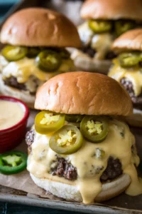 Serve burgers hot with queso sauce and jalapeños