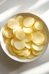 Slice the potatoes into thin rounds and soak them in water