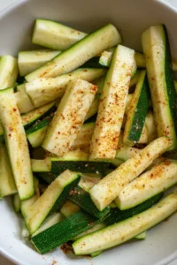 Slice zucchini into thin strips and season with olive oil and spices