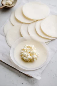 Soak rice paper sheets in lukewarm water and fill with cheese