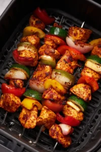 Thread marinated chicken and cut vegetables onto skewers and place them in the air fryer basket