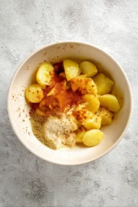 Toss the potatoes with olive oil, paprika, garlic powder, onion powder, salt, and black pepper in a mixing bowl until evenly coated