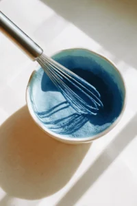 Whisk blue matcha powder and lukewarm water together until smooth and frothy