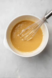 Whisk together wet ingredients including applesauce, honey, protein powder, and eggs until smooth