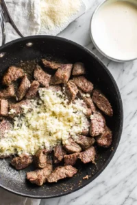 Add minced garlic and cook until fragrant, pour in heavy cream and stir in parmesan cheese, simmer until sauce thickens and mix with cooked pasta