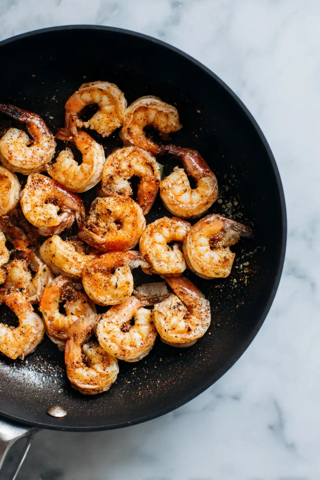 Add shrimp to skillet and season with Cajun seasoning