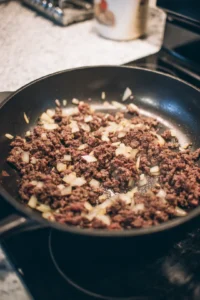 Brown ground beef, onion, and garlic in a large skillet
