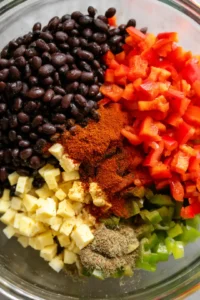 Combine black beans, vegan cheese, diced bell peppers, cumin, and smoked paprika in a mixing bowl