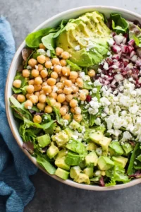 Combine chickpeas, diced avocado, feta cheese, and salad greens in a bowl
