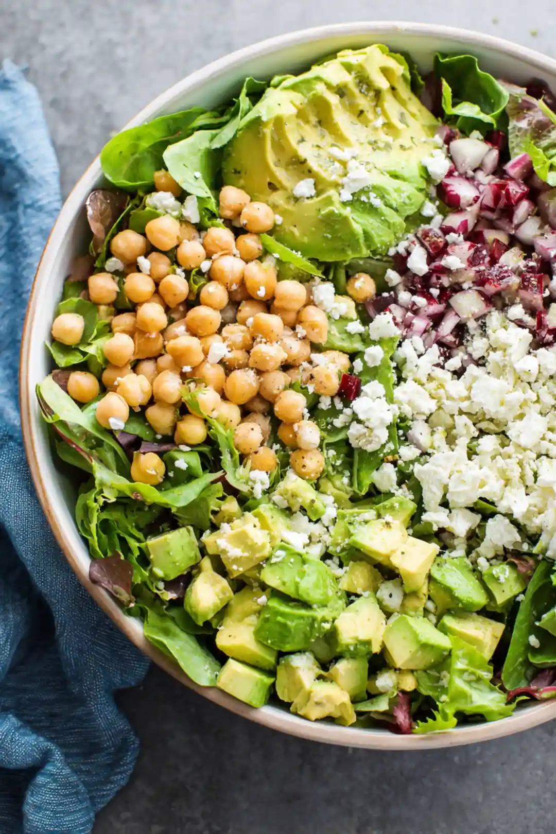 Combine chickpeas, diced avocado, feta cheese, and salad greens in a bowl