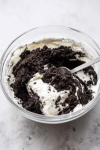 Combine crushed Oreo cookies and softened cream cheese in a mixing bowl