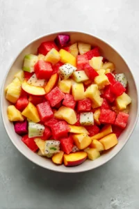 Combine diced fresh peaches, watermelon, pineapple, and dragon fruit in a large mixing bowl
