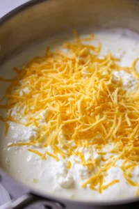 Combine Greek yogurt, shredded cheddar cheese, and cottage cheese in a saucepan until melted and creamy