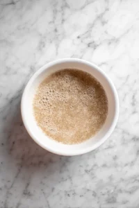 Combine lukewarm water, sugar, and yeast in a bowl and let it sit until frothy