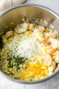 Combine shrimp, bread crumbs, cheddar cheese, parsley, lemon juice, garlic powder, salt, and pepper in a mixing bowl
