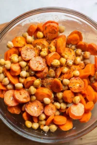 Combine sliced carrots and chickpeas with olive oil, cumin, paprika, salt, and pepper