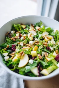 Combine the mixed salad greens, diced apples, and crumbled feta cheese in a large salad bowl