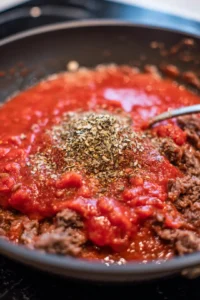 Combine tomato sauce and Italian seasoning with the beef mixture, then stir and simmer. Mix in cooked rigatoni and cheeses, pour into a baking dish, and bake until golden brown.