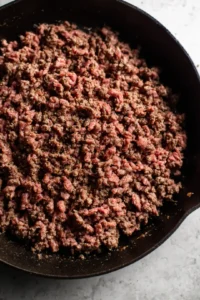 Cook ground beef in skillet until browned and seasoned with salt and pepper