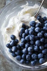 Gently fold in the fresh blueberries, ensuring an even distribution throughout the yogurt.
