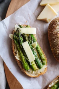 Heat a skillet over medium heat, spread butter on one side of each slice of bread, layer cheese and asparagus on the unbuttered side, and top with another slice of bread.