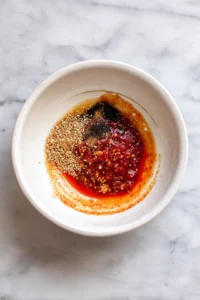 Mix together gochujang, soy sauce, sesame oil, minced garlic, and maple syrup