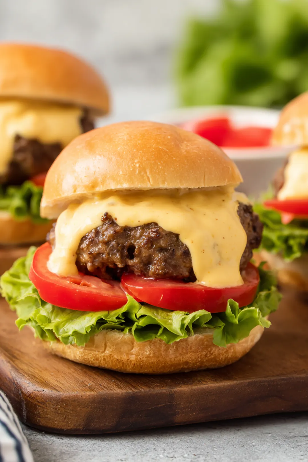 Place each burger patty on a bun and top with queso dip, lettuce, and tomato
