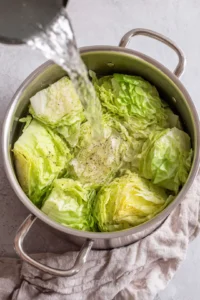Pour water to cover cabbage halfway and sprinkle with salt and pepper