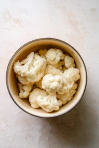 Preheat oven to 425 degrees Fahrenheit and cut cauliflower into florets