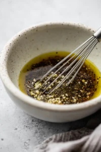 Prepare the dressing by whisking together olive oil, red wine vinegar, Dijon mustard, honey, and minced garlic
