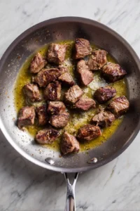 Sear steak pieces in skillet with butter and seasonings