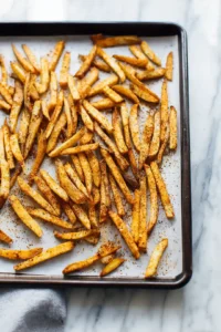 Spread seasoned fries on baking sheet and bake until golden