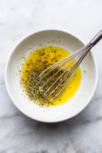 Whisk together the olive oil, lemon juice, oregano, and garlic powder in a small bowl